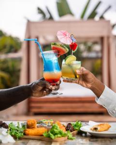 two people holding up drinks on a table at D.D. Amazonica Bungalows in Landsboerderij