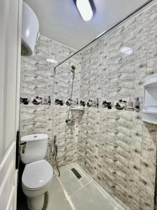 a bathroom with a toilet and a stone wall at Famille Hanae appartement avec terasse in Marrakech