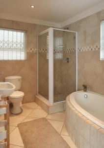 a bathroom with a tub and a toilet and a sink at Shell Shores -Apartment with balcony, Sea views and private parking in Jeffreys Bay