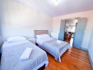 two beds in a small room with wood floors at Janela da Vesperata in Diamantina