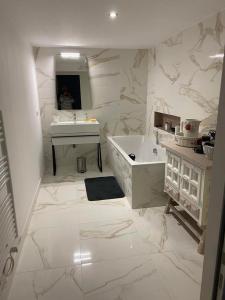 a white bathroom with a tub and a sink at Le volcan in Rochefort