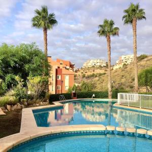 een groot zwembad met palmbomen en gebouwen bij Nice apartment with terrace in Bonalba Golf in Mutxamel