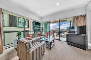 a living room with two couches and a television at Fabulous Corner Apartment w/ Dazzling Harbour View in Auckland