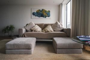 uma sala de estar com um sofá e um repousa-pés em Penthouse at the Chocolate Box em Bournemouth
