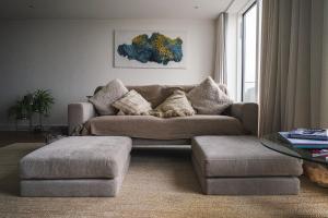 a living room with a couch and a ottoman at Penthouse at the Chocolate Box in Bournemouth