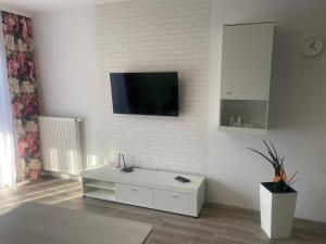 uma sala de estar com televisão numa parede branca em 1 Tyskie Apartamenty z ogródkiem em Tychy
