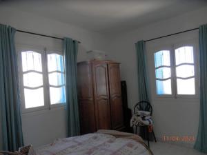 FafouにあるVilla Amine MGのベッドルーム1室(ベッド1台、窓2つ、木製キャビネット付)