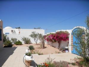 a white building with flowers and plants in front of it at Villa Amine MG in Fafou