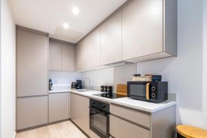 una cucina con armadietti bianchi e forno a microonde di Elegant central apartment a Milton Keynes