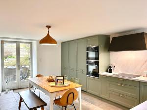 a kitchen with green cabinets and a wooden table at Maison La Cassine Saint-Ceneri-le-Gerei in Moulins-le-Carbonnel