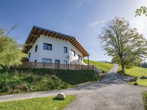 a white house with a wooden roof on a hill at Haus SaRo in Hopfgarten im Brixental