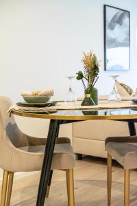 米爾頓凱恩斯的住宿－Elegant central apartment，餐桌,玻璃顶和椅子