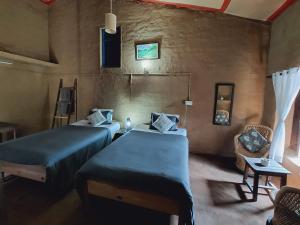 Habitación con 2 camas y una silla. en Kurmanchal Village by THE GHAUR, en Almora