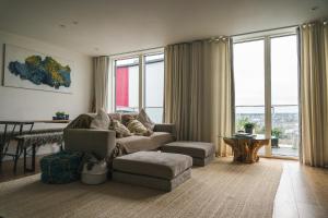 a living room with a couch and a table and windows at Penthouse at the Chocolate Box in Bournemouth