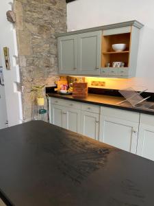 cocina con armarios blancos y encimera negra en Converted chapel - Sant Pedr Newydd - with sea views en Amlwch