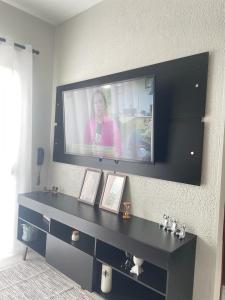 Ein Fernseher an der Wand mit einer Frau drauf. in der Unterkunft Condomínio Moradas da Vila in Imbituba