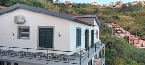ein weißes Gebäude mit grünen Rollläden auf einem Hügel in der Unterkunft Vista Funchal in Funchal