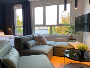 a living room with a couch and a bed and windows at Karls Apartment - B24 in Gera