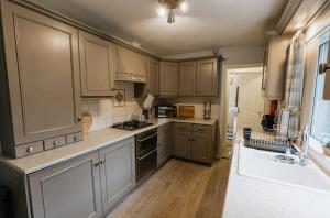 a kitchen with wooden cabinets and a sink at Winnie's Cottage - 3 Bed Accommodation in Cumbria in Mealsgate