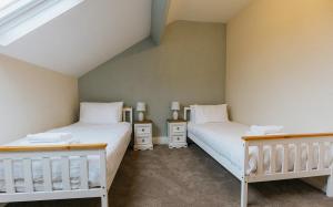two beds in a room with white walls at Winnie's Cottage - 3 Bed Accommodation in Cumbria in Mealsgate