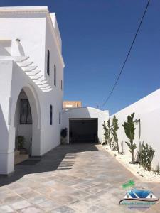 um edifício branco com uma garagem e uma entrada em Villa Amine Flouka em Houmt Souk