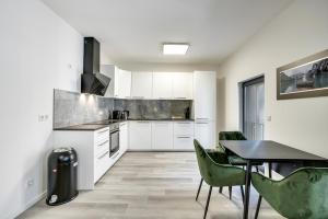 uma cozinha com armários brancos e uma mesa e cadeiras em Mont Apartments em Düsseldorf
