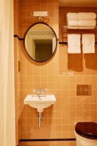 uma casa de banho com um lavatório, um espelho e um WC. em Grand Hotel Bellevue London em Londres