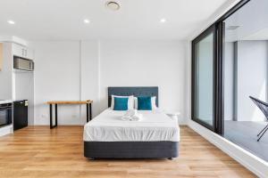 a bedroom with a large bed with blue pillows at Manukau Studio Apartments in Auckland