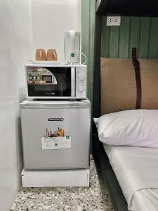 a microwave on top of a refrigerator next to a bed at Cebu Backpackers Hostel in Cebu City
