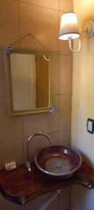 Un lavabo en un baño con un espejo y una lámpara. en Cafuné Cabañita Sur, en El Bolsón