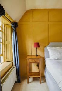 a bedroom with a bed and a table with a lamp at Clarendon Cottage in Enfield