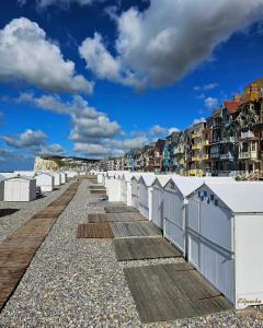 Une rangée de cabanes de plage sur une plage rocheuse dans l'établissement Studio La Cabine, à Mers-les-Bains