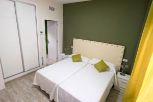 una camera da letto con un letto bianco e pareti verdi di CASA CON PATIO a Pozoblanco
