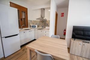 eine Küche mit einem Holztisch und einem weißen Kühlschrank in der Unterkunft Apartamentos 7 puentes sierra Cazorla Casa Acebo in Burunchel