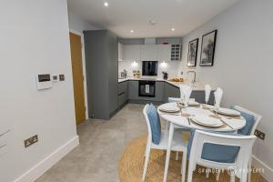a kitchen and dining room with a white table and chairs at Newly Built 2br Apartment near Sandy Beaches and Tuckton Village - Meraki Vista in Bournemouth