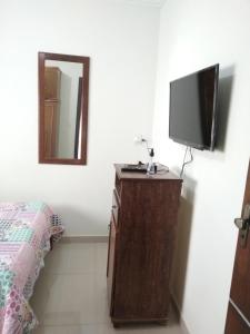 um quarto com uma cama e uma televisão numa cómoda em Bom Jardim em Piumhi