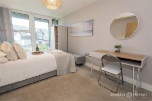 a bedroom with a bed and a mirror and a chair at Newly Built 2br Apartment near Sandy Beaches and Tuckton Village - Meraki Vista in Bournemouth