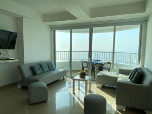 una sala de estar con sofás y vistas a un balcón. en Hermoso edificio de frente al mar, en Cartagena de Indias