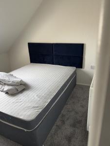 um pequeno quarto com uma cama com uma cabeceira azul em Excellent 3bed flat em Kent