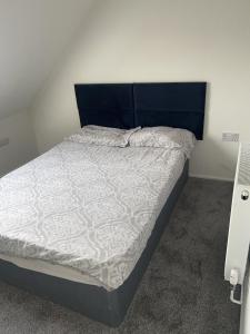 a bed with a blue headboard in a bedroom at Excellent 3bed flat in Kent