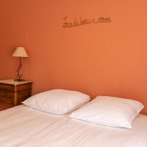 a bed with two pillows and a sign on the wall at Gîte de la Gare aux Fleurs 