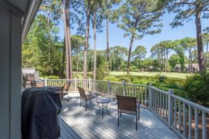 a deck with chairs and tables and palm trees at 12 Isle of Pines in Hilton Head Island