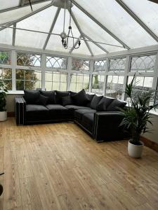 a black leather couch in a large room with windows at A beautiful Large 7 bed house in Porthcawl