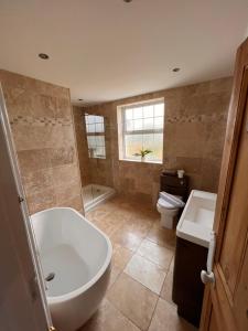 a bathroom with a tub and a sink and a toilet at A beautiful Large 7 bed house in Porthcawl
