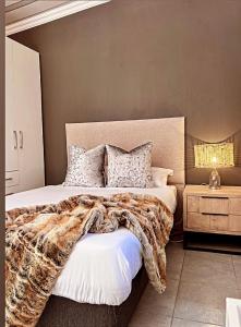 a bedroom with a large bed with a blanket at La Creme Ilanga Waterkloof in Pretoria