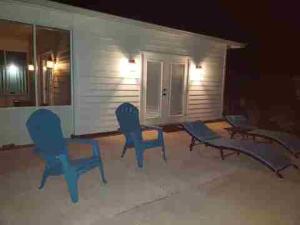 eine Terrasse mit blauen Stühlen, einem Tisch und einem Haus in der Unterkunft The Lounge 