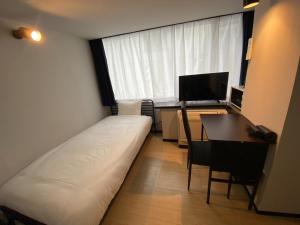 Habitación pequeña con cama, escritorio y ventana. en ＰＩＡＺＺＡーＵ - Vacation STAY 78021v, en Tokio