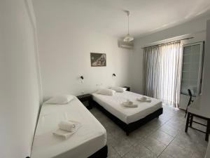 two beds in a room with white walls at Deep Blue Rooms & Apartments in Mylopotas