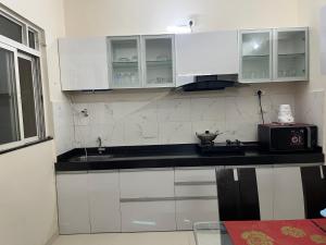 a kitchen with white cabinets and a black counter top at Little nest Homestay in Pune