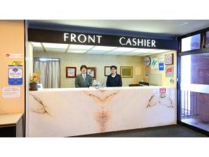 Hotel Silk in Madarao - Vacation STAY 79652v في Iiyama: رجلان واقفان في مكتب الصراف الأمامي